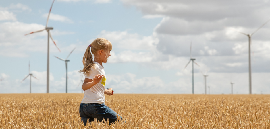 Een meisje rent door een weiland met windmolens