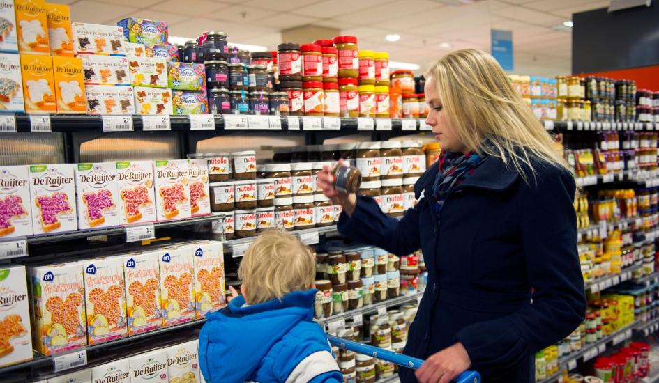 Vrouw en kind in boodschappenkar supermarkt