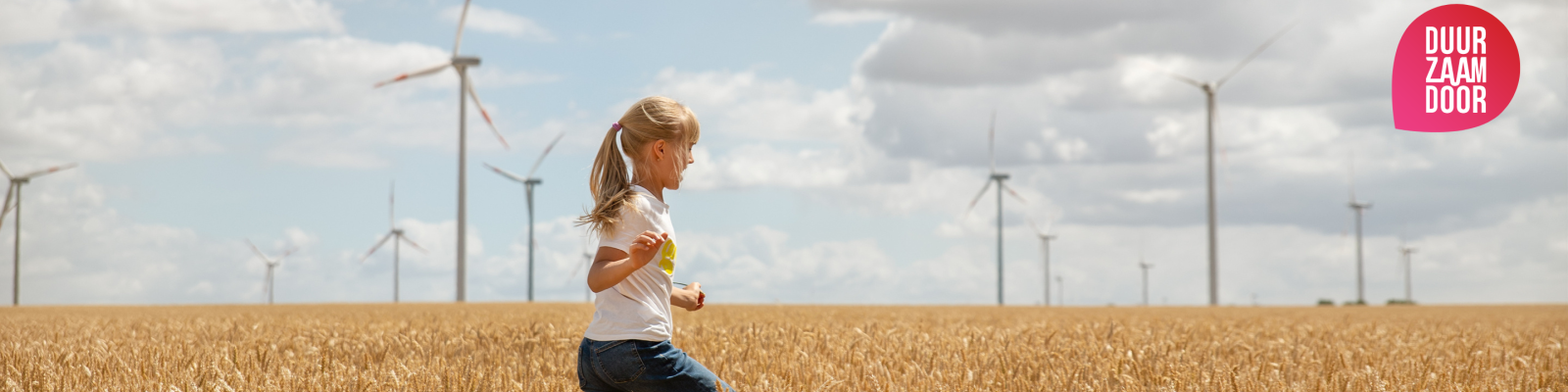 Een meisje rent door een weiland met windmolens